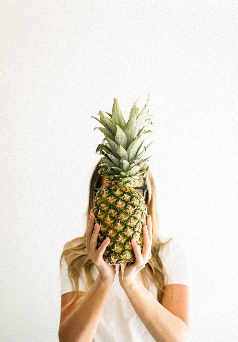 Caitlin MacDougald, founder of CM SWIM CO, playfully holding a pineapple in front of her face