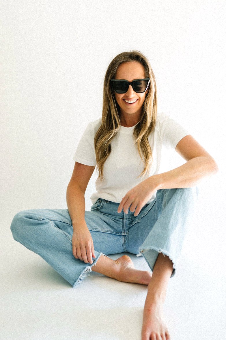 Caitlin MacDougald, founder of CM SWIM CO, smiling in a white tee and jeans